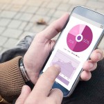 Men’s Hands working with smartphone with financial report on scr