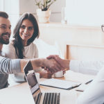 Good deal! Cheerful young man bonding to his wife while shaking