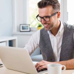 Young happy designer working on laptop from home – freelance con