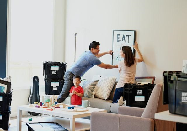 Young couple with a child hanging pictures in their newly decorated rental apartment